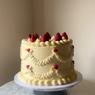 The cream buttercream cake with piped swags and fresh strawberries this comment was left on