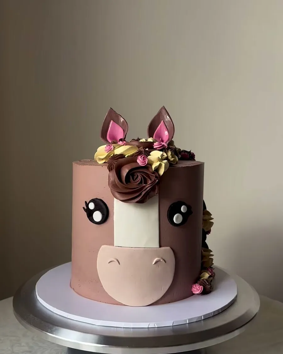 A brown buttercream cake sculpted into a horse face with piped mane and ears