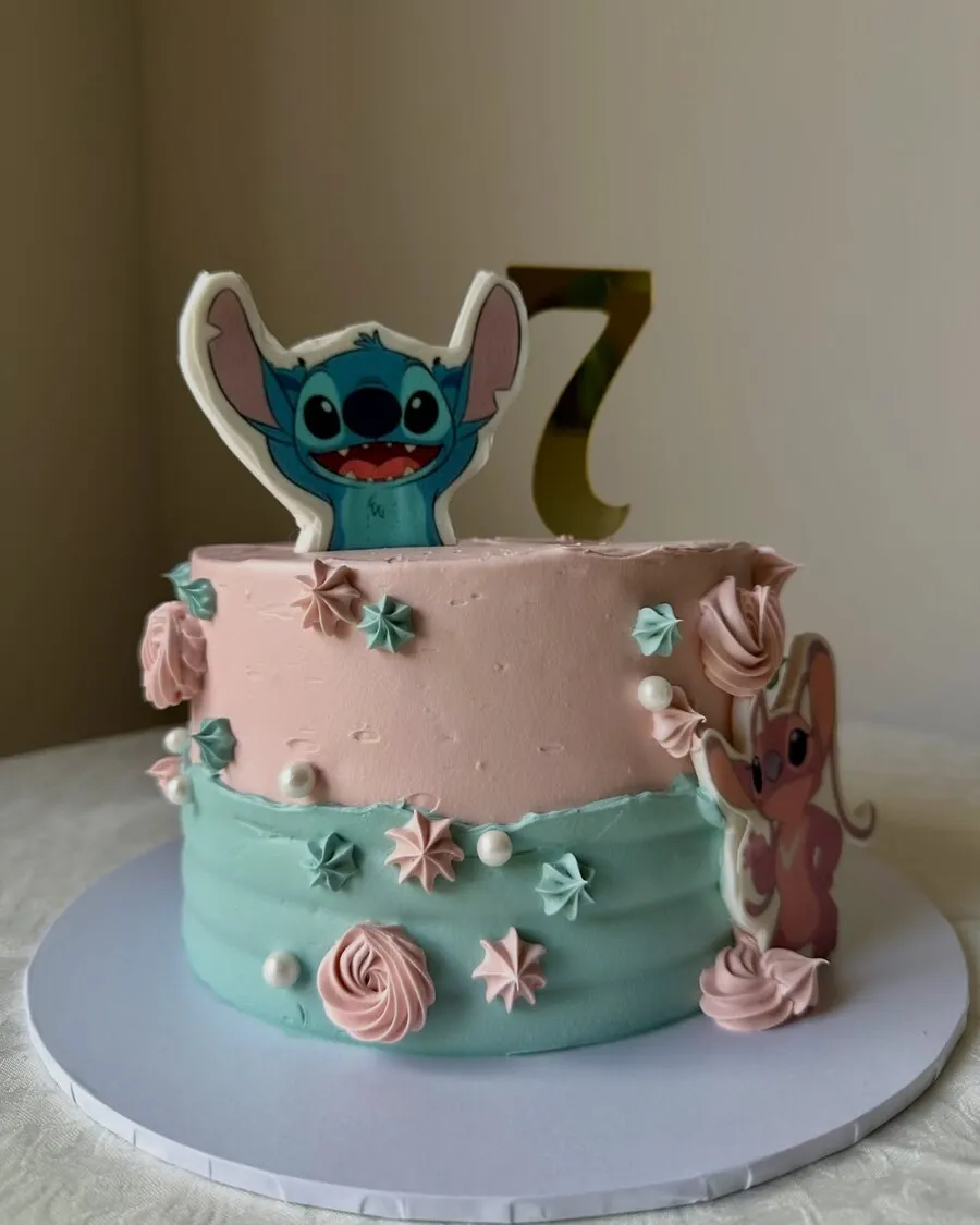 A pink and aqua buttercream cake with a Stitch topper and a gold number seven
